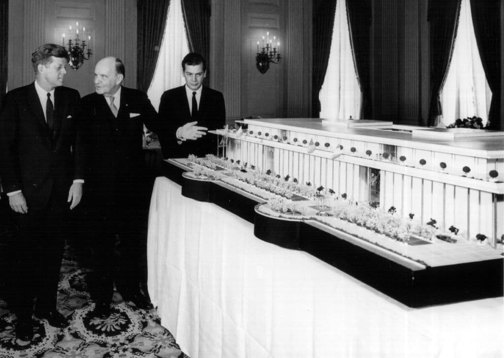 Black and white photo of President John F. Kennedy and officials looking at a small model of the yet-to-be-built Kennedy Center.