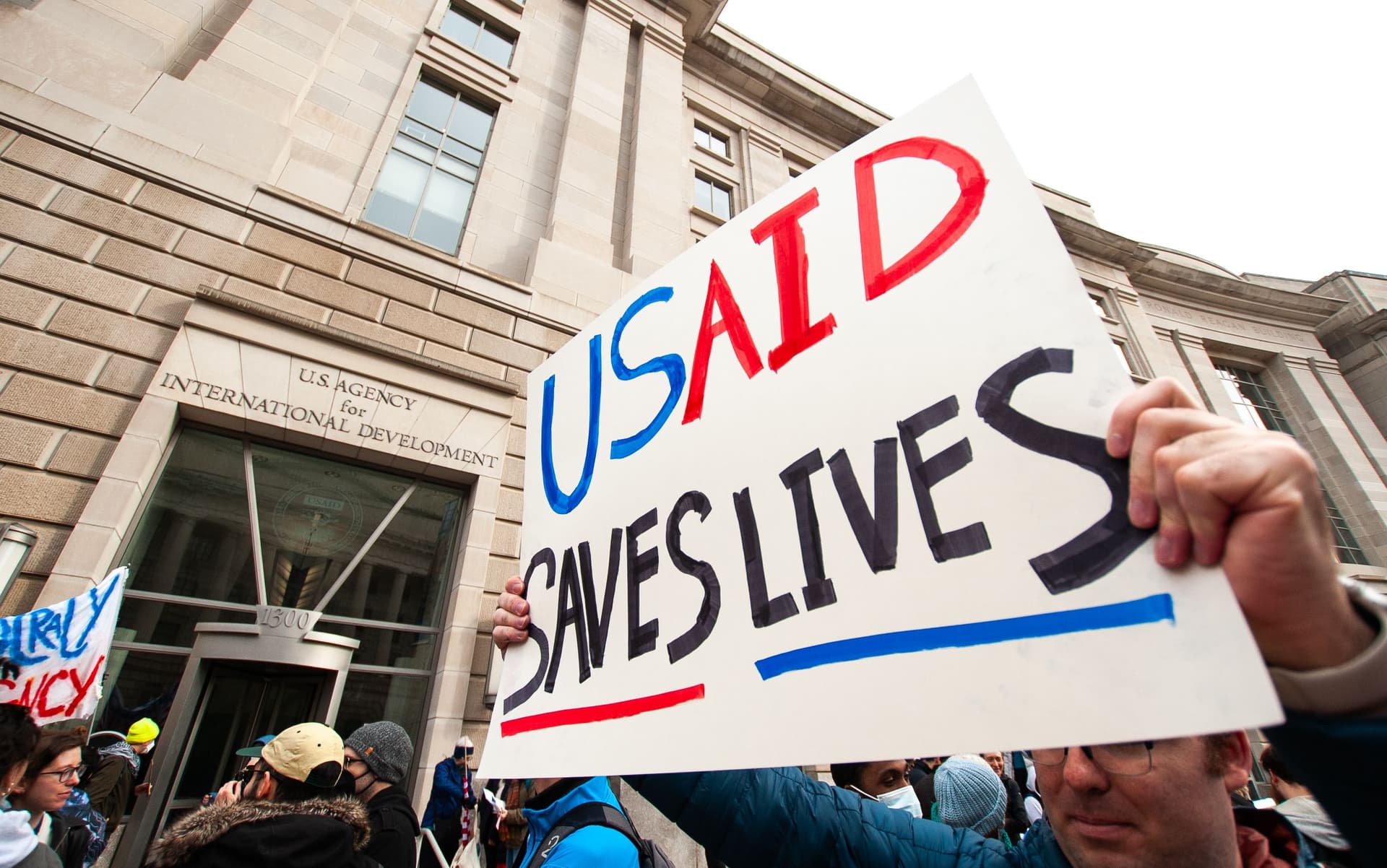 USAID supporters gather outside shuttered headquarters on Monday afternoon.