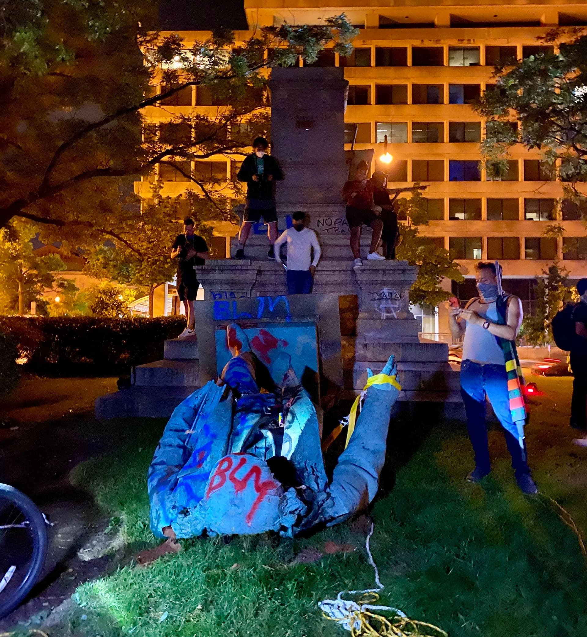 People standing on top of the pillars of the stone that was below the statue and witnessing the toppled statue of Confederate General Albert Pike near 3rd and D streets Northwest on June 19, 2020.